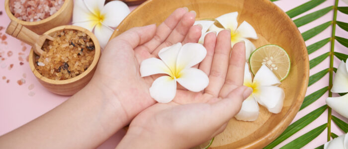 Woman soaking her hands in bowl of water and flowers, Spa treatm
